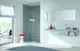 Weißer Durchlauferhitzer von Viessmann, wandmontiert, neben einem großen Spiegel und Waschbecken in modernem Badezimmer mit Dusche und natürlichem Licht von außen.